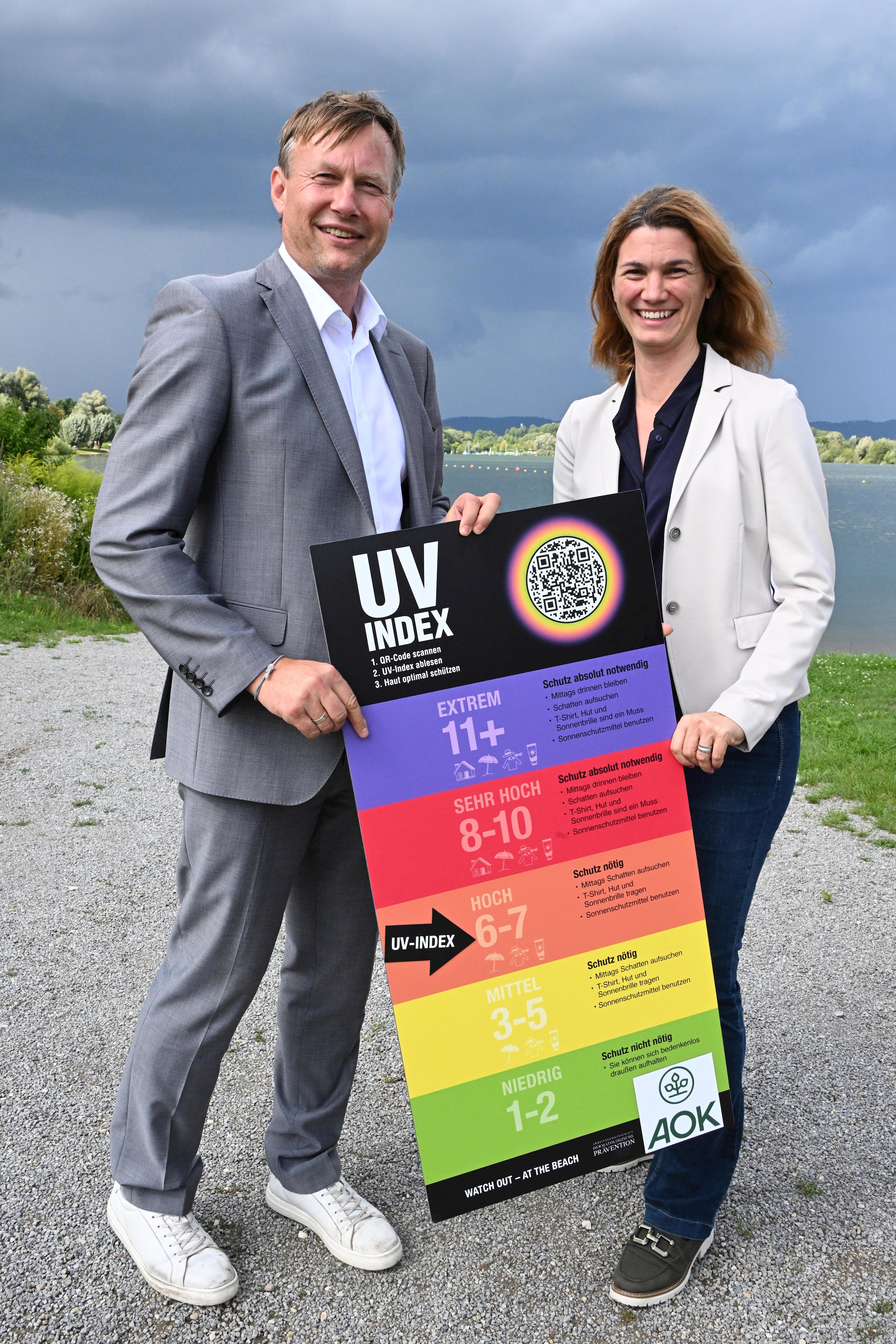 2 Personen mit einer UV-Index-Tafel